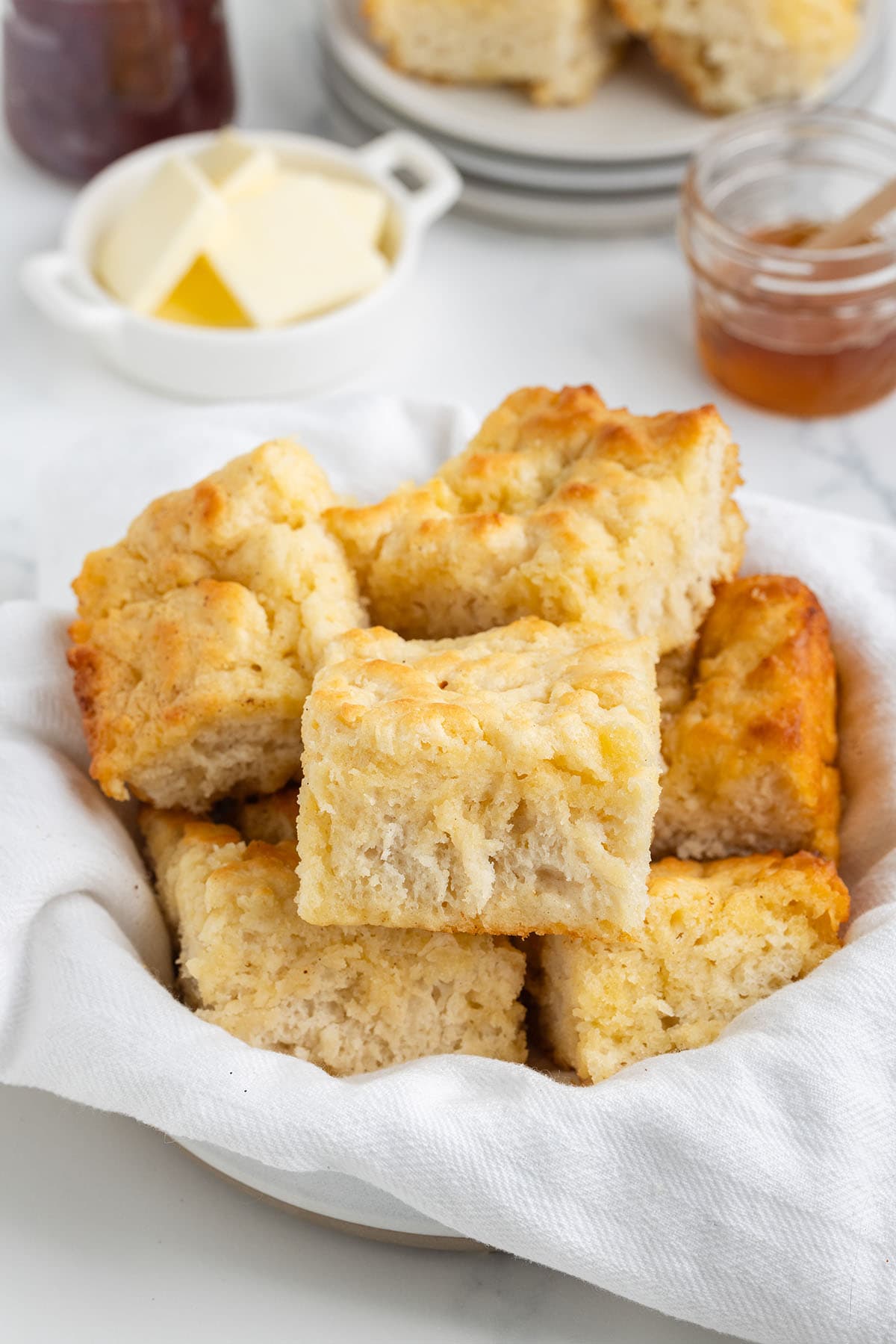 a basket of Butter Swim Biscuits with honey and butter in the background.