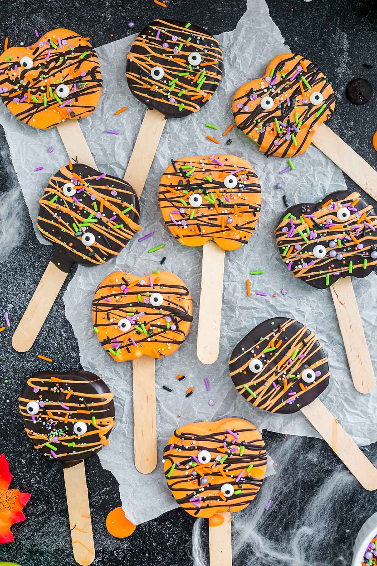 a couple of Halloween Chocolate Covered Apple Pops scattered on the table.