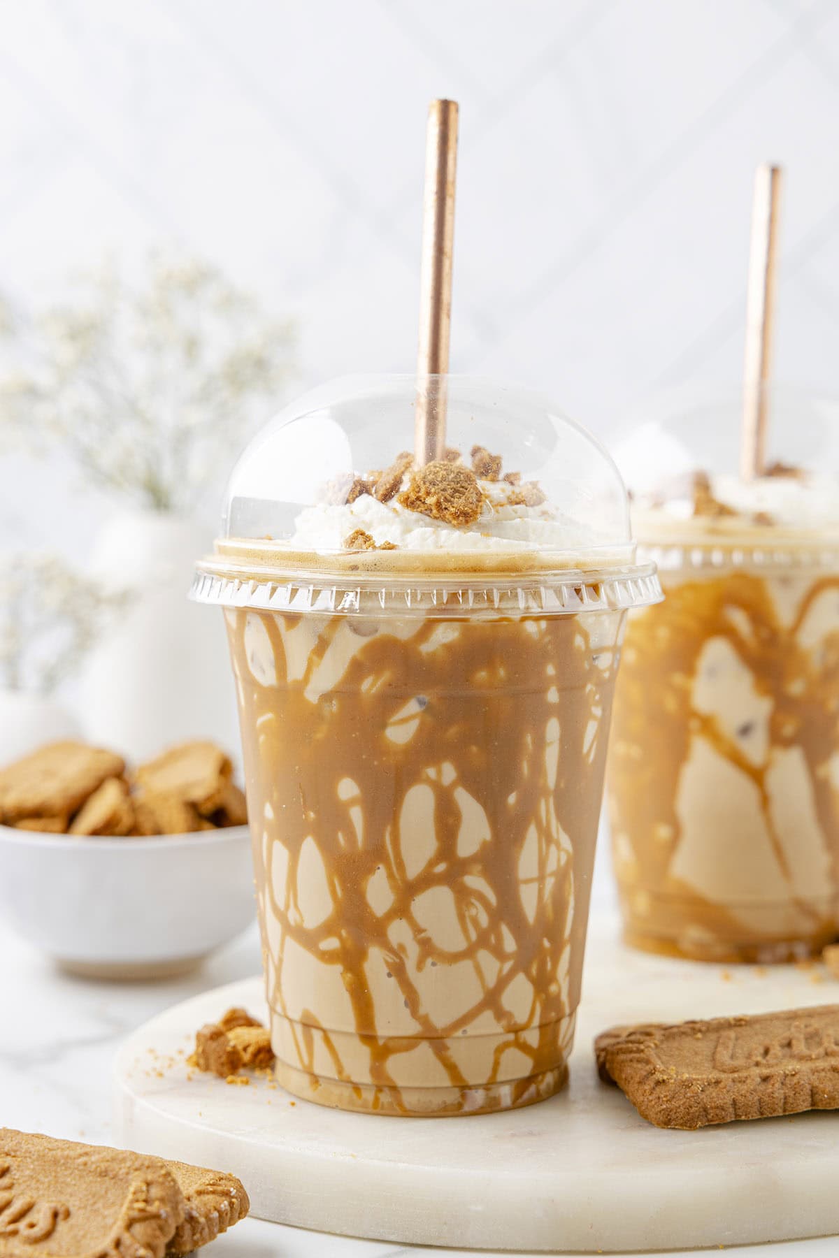 Iced Cookie Butter Latte in a plastic cup topped with whipped cream and crumbled cookies.