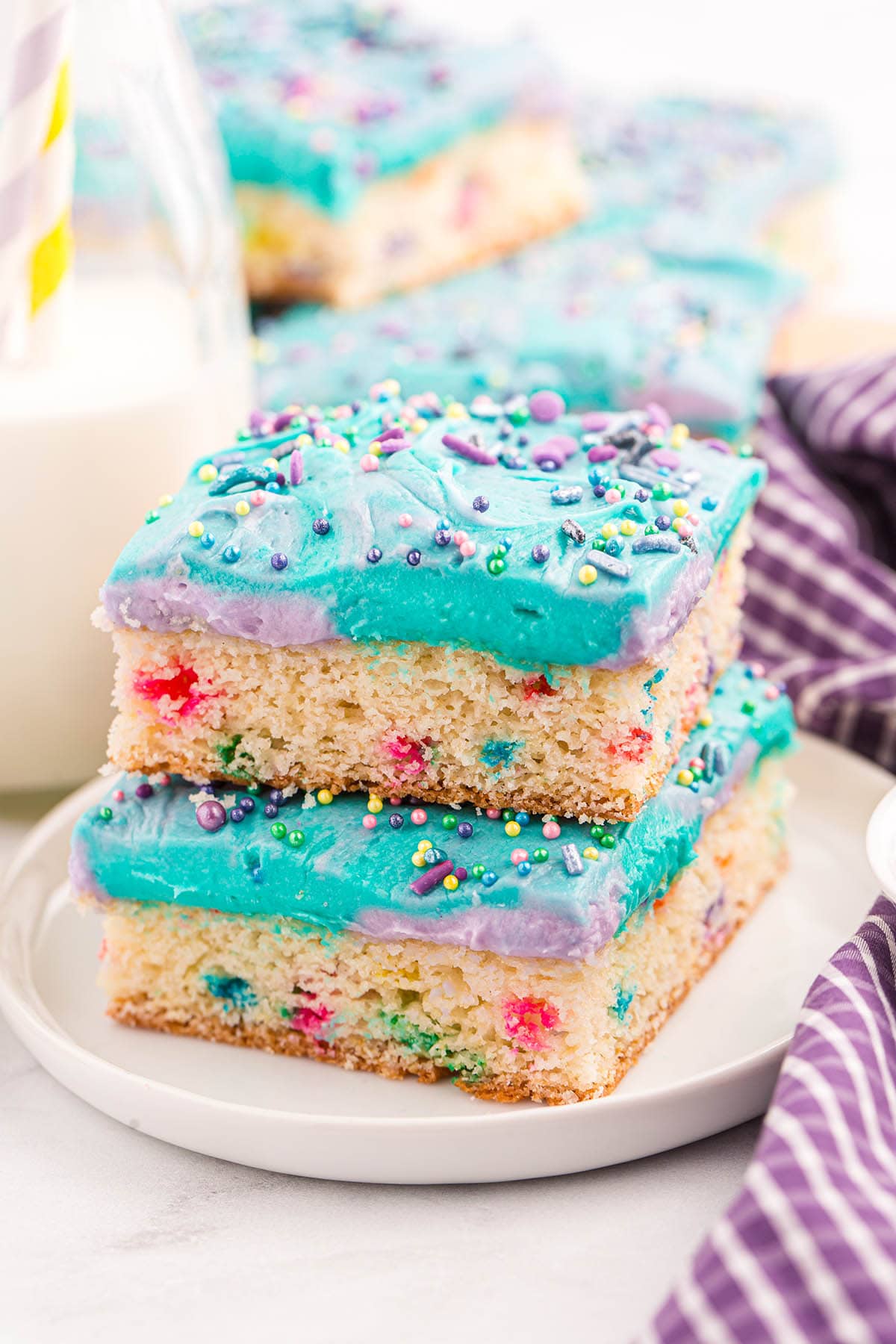 a stack of Unicorn Bars on a white plate topped with sprinkles.