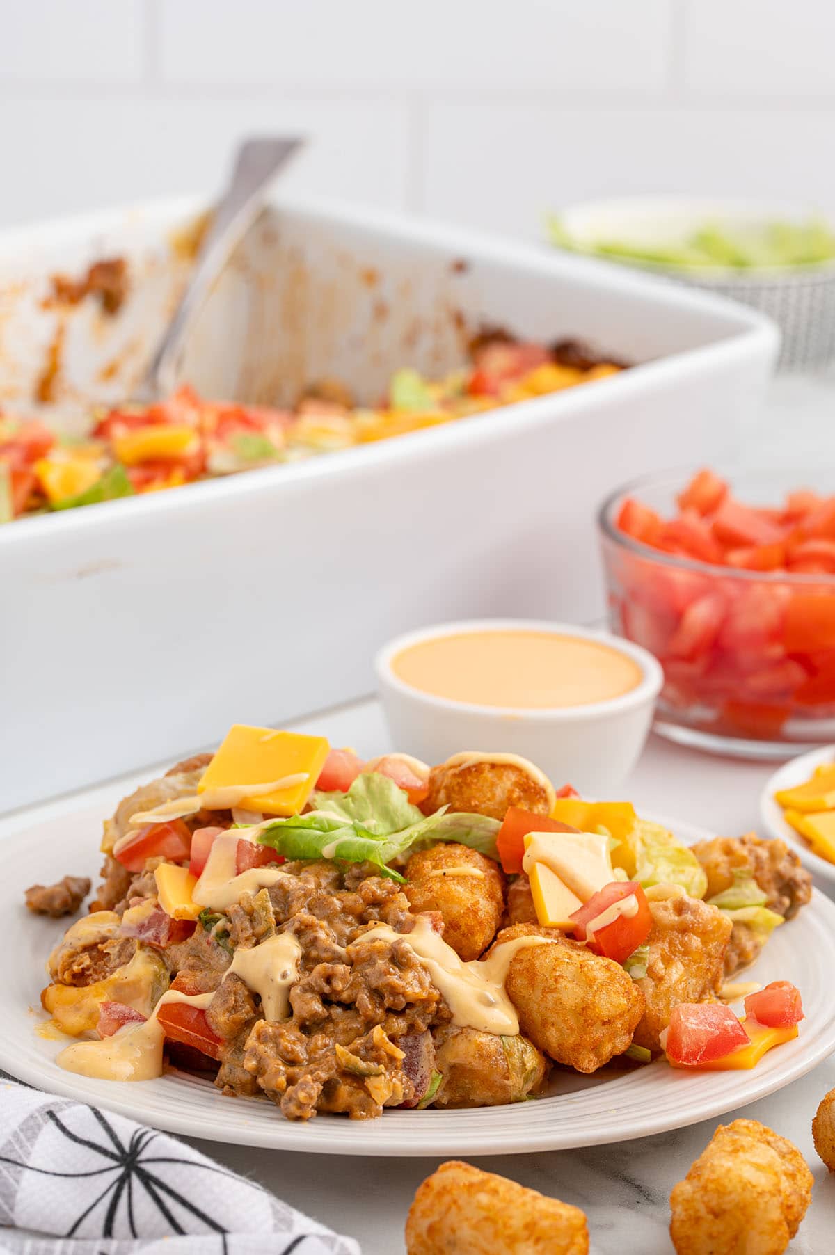 a plate of Big Mac Tater tot Casserole on the table drizzled with thousand island dressing.