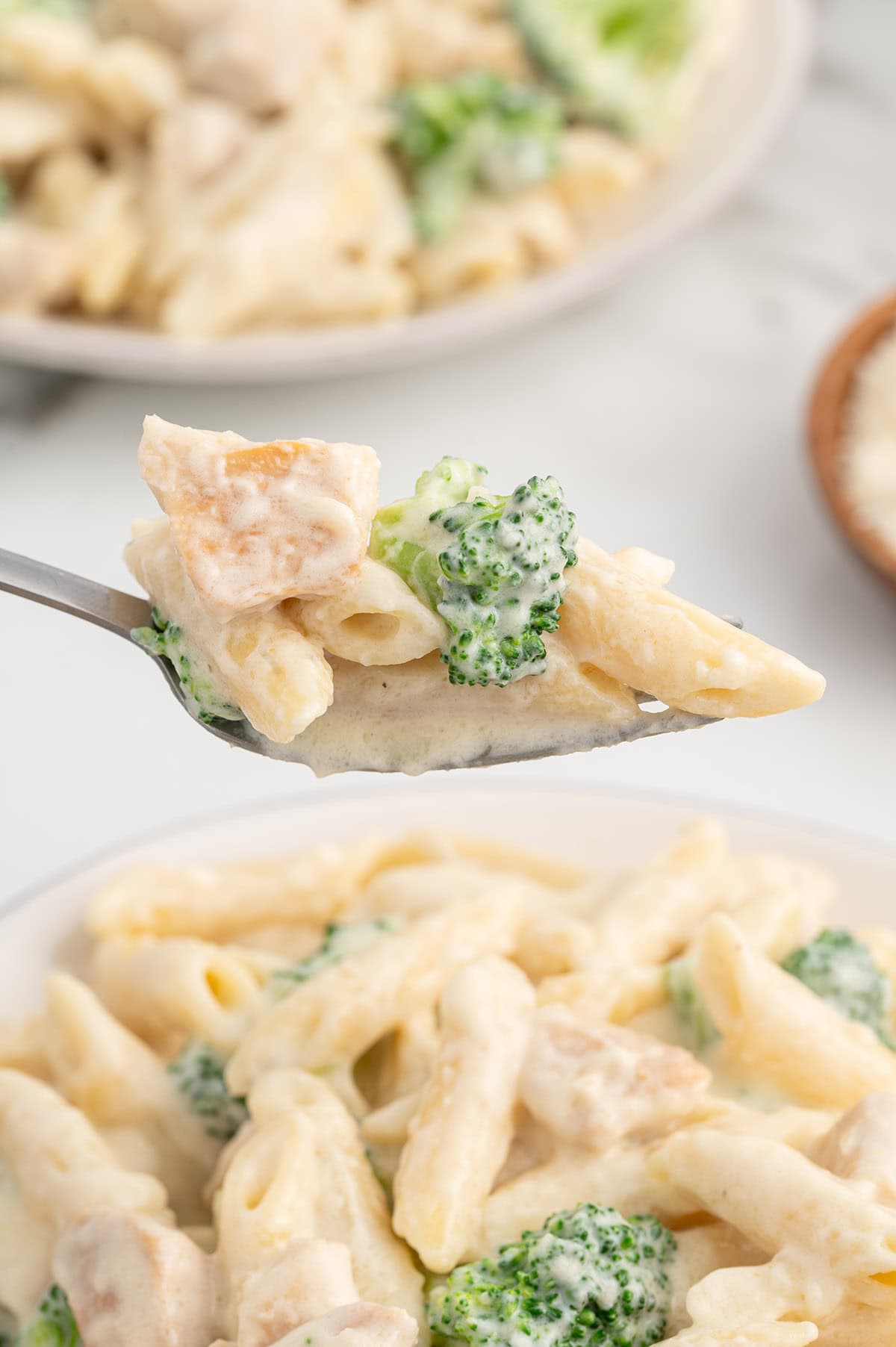 eating Chicken and Broccoli Penne Alfredo with a fork. 