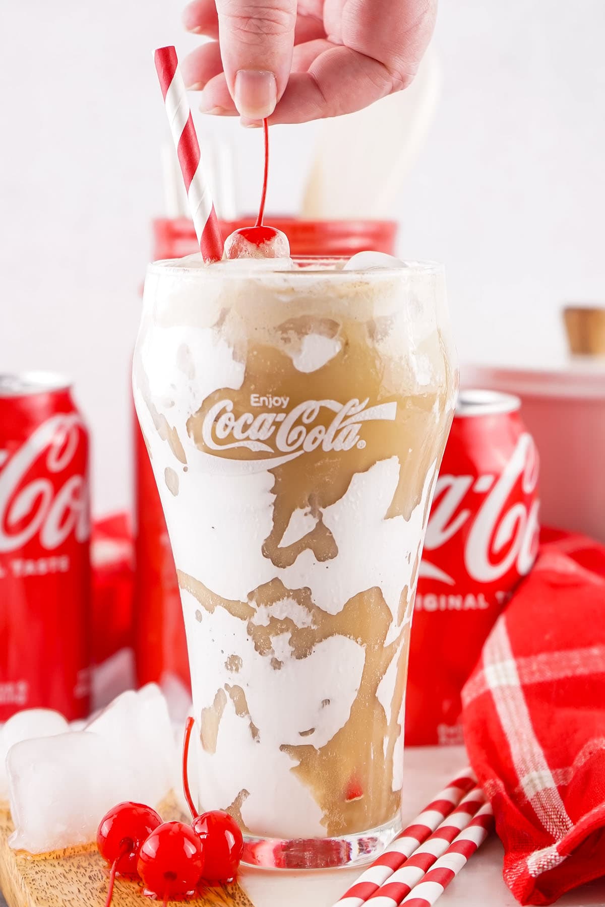 a glass of Fluffy Coke with a straw and a cherry on top.