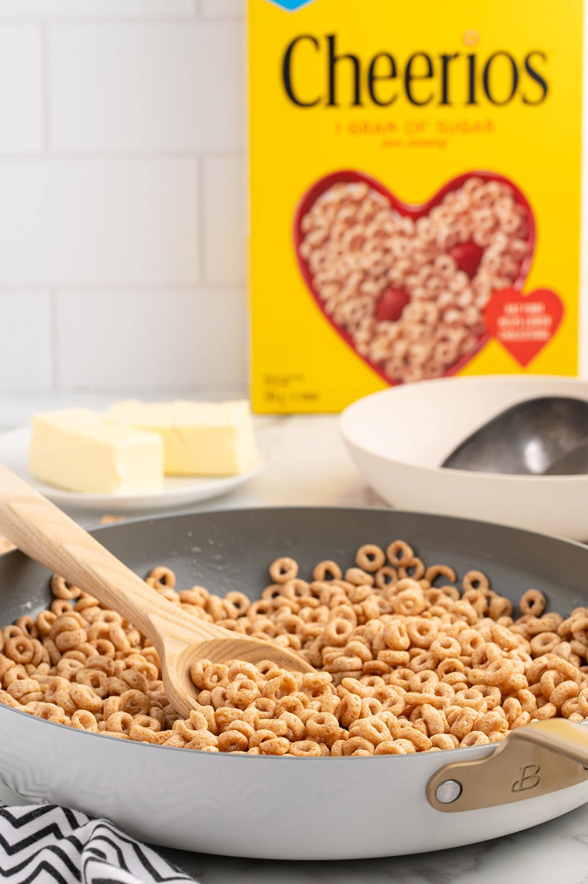 hot buttered cheerios in a skillet with a box of Cheerios in the background. 