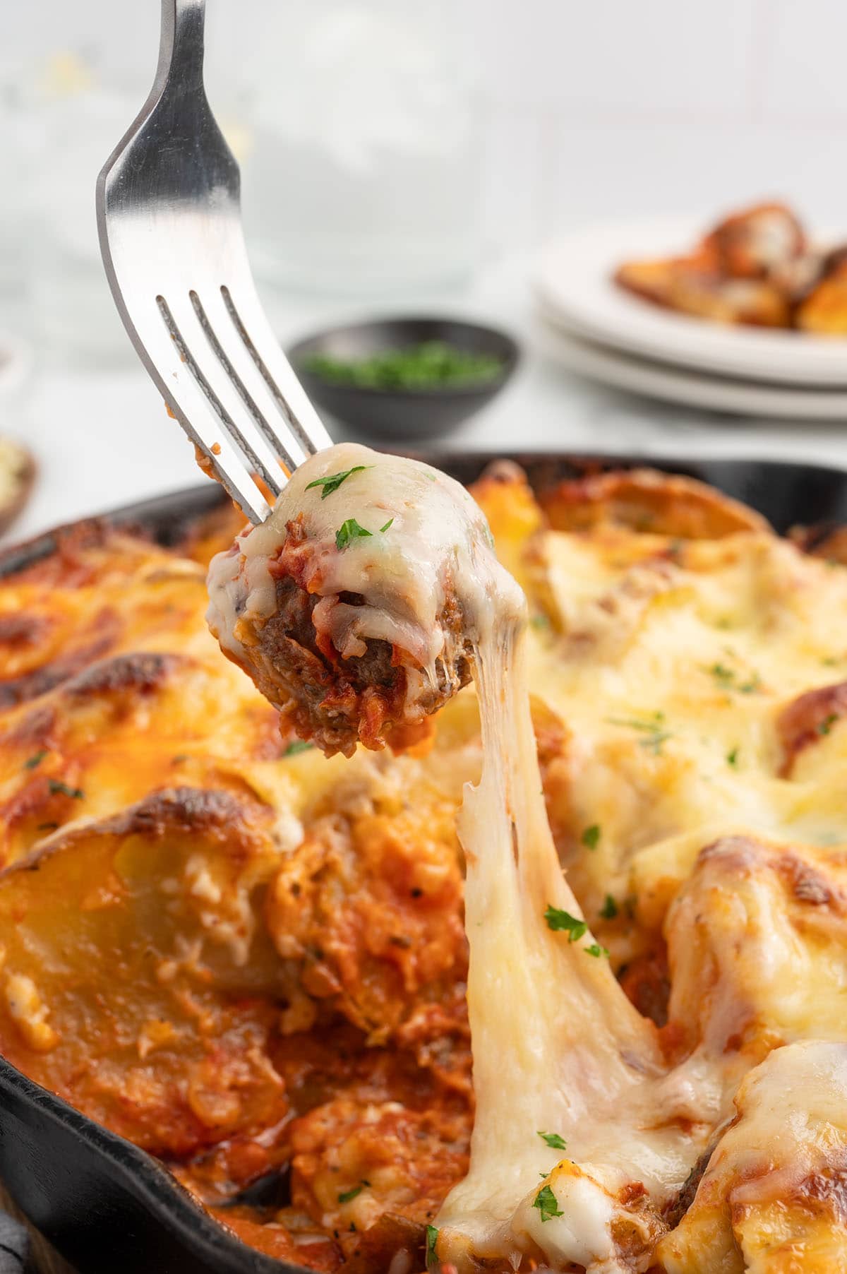 a fork lifting a Meatball from the skillet.