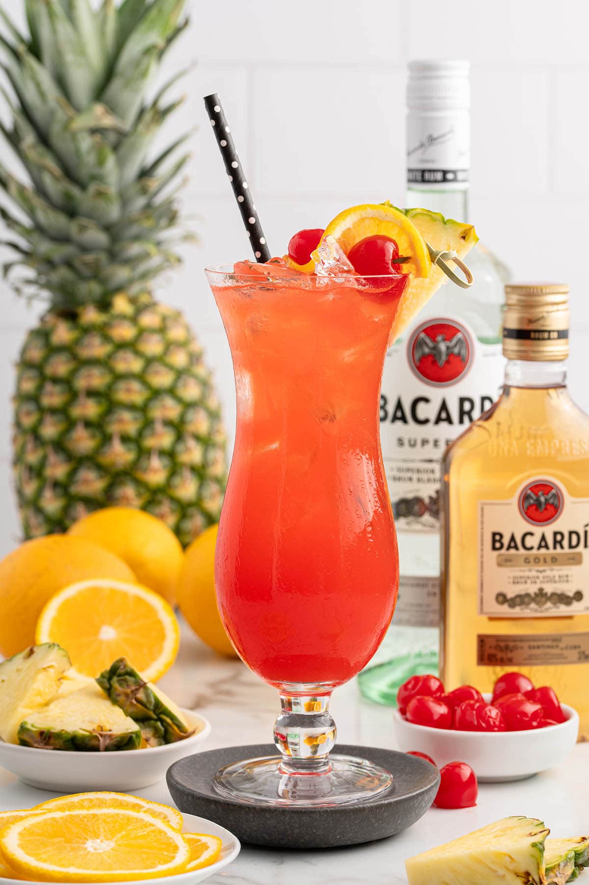 a glass of Rum Punch garnished with a lemon wheel, pineapple slice and maraschino cherries.