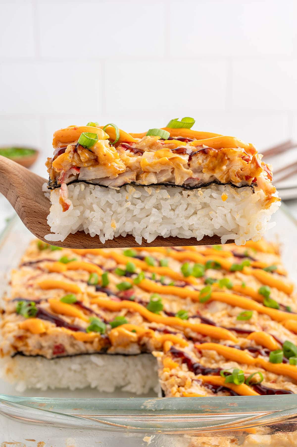 a slice of Sushi Bake being lifted from a baking dish with a wooden spatula.