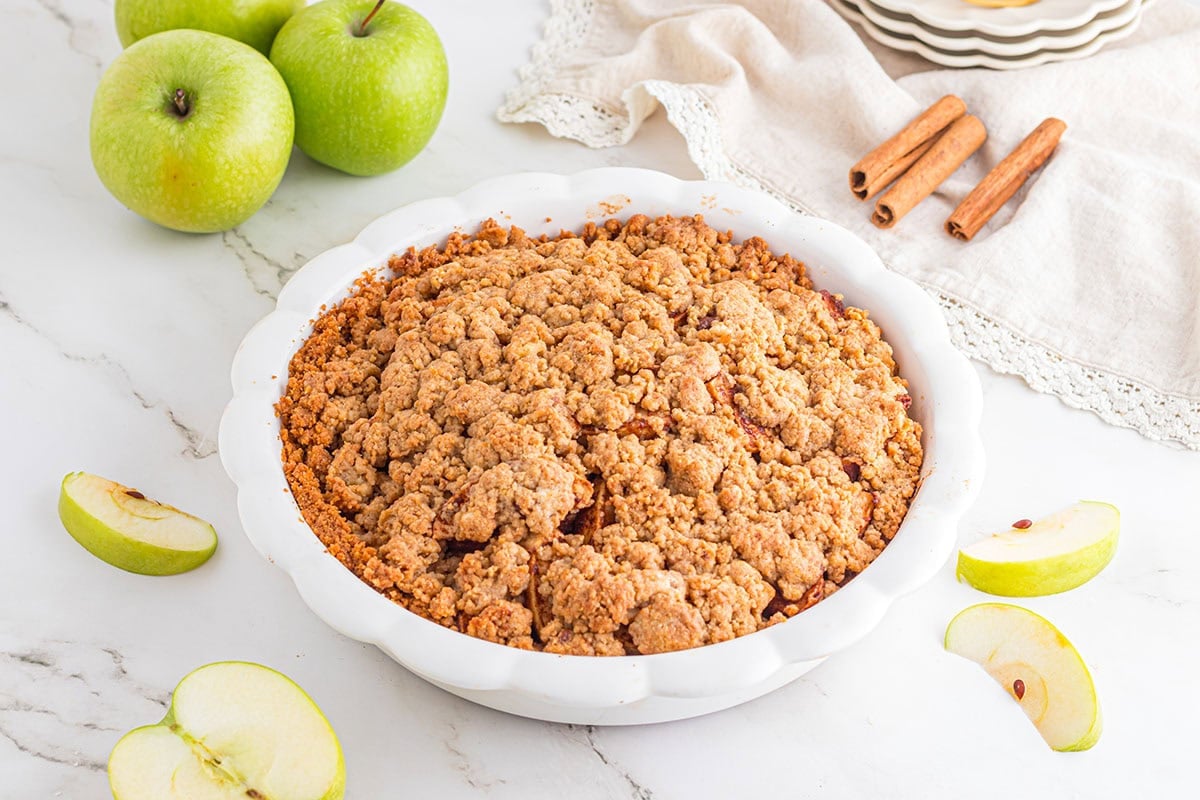 Apple Pie with Graham Cracker Crust in a pie dish on a white table.