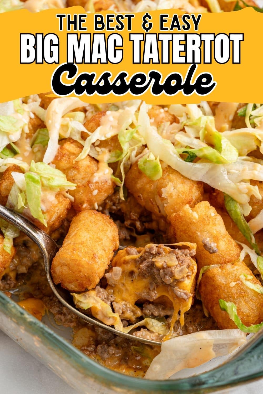 A stainless steel spoon digging into hearty Big Mac Tatertot Casserole in a glass baking dish.