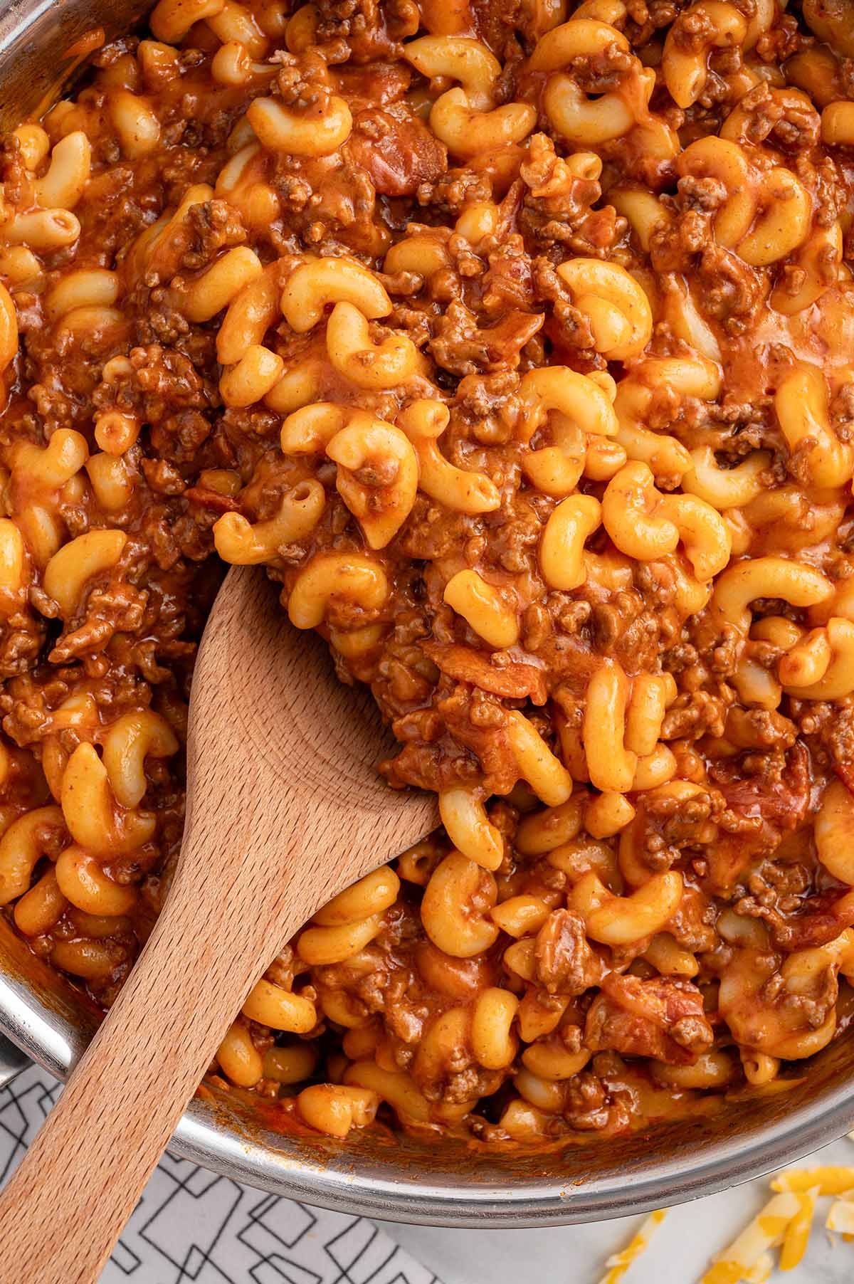 Bacon Cheeseburger Pasta in a skillet with a wooden spoon.