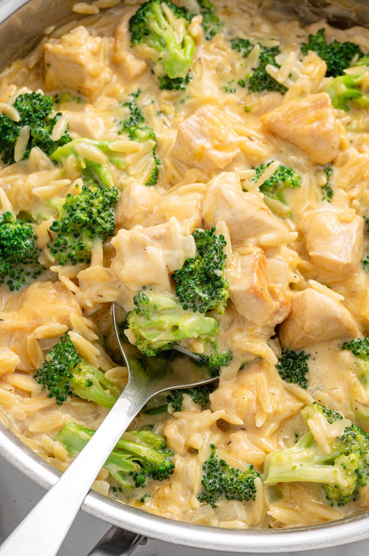 cheesy chicken orzo with broccoli on a large skillet.