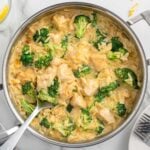 a large skillet filled with cheesy chicken orzo and broccoli florets.