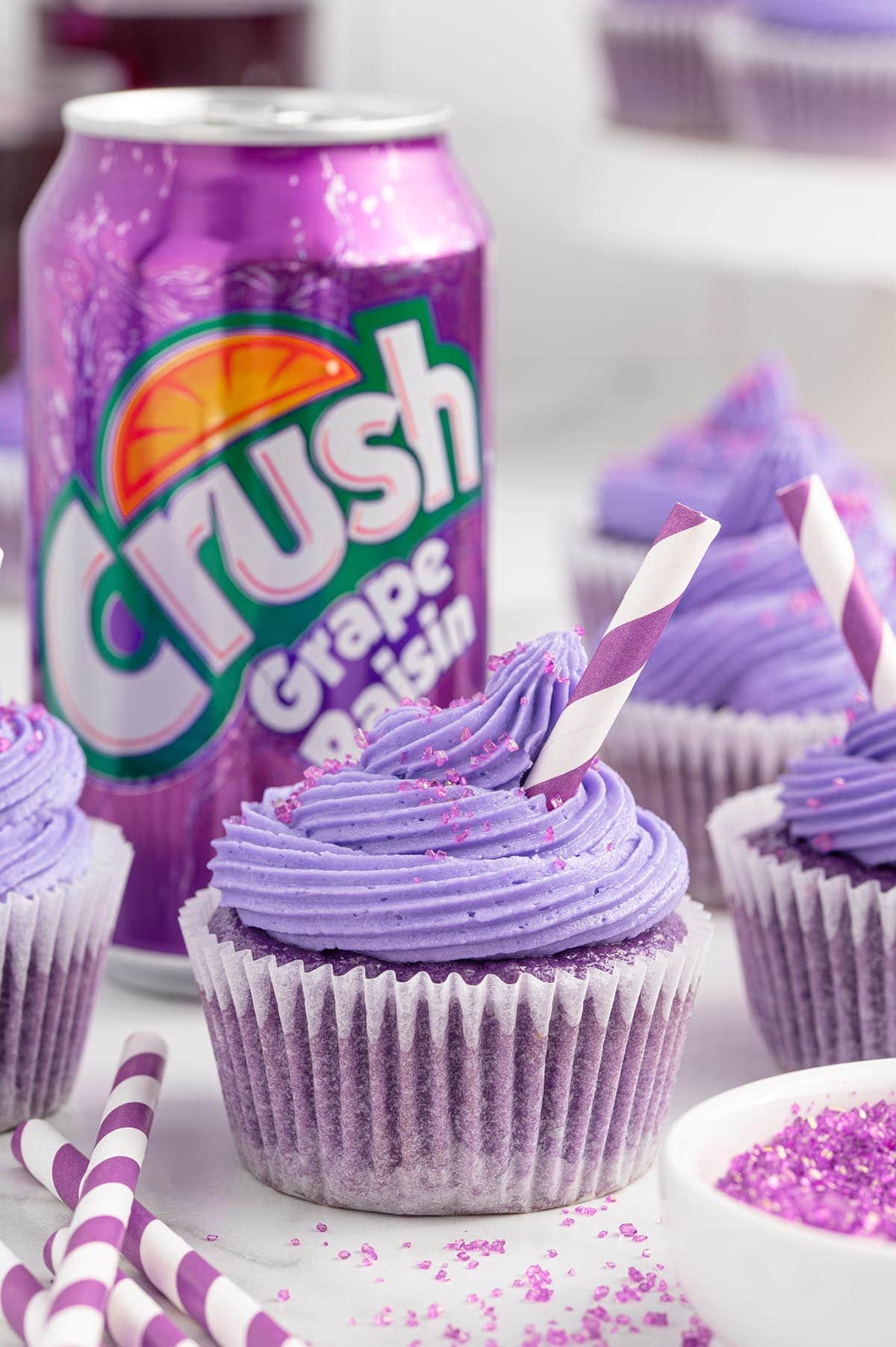 a grape soda cupcake topped with purple frosting and sprinkle of sparkling sugar.