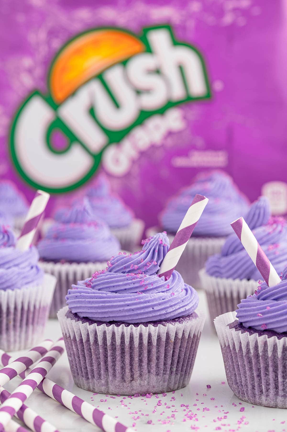 a couple of grape soda cupcakes on the table.