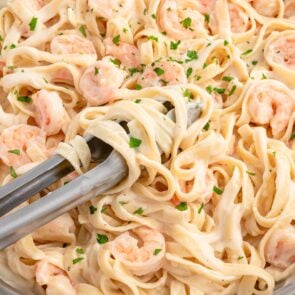 a pan of Shrimp Pasta Alfredo garnished with chopped parsley.