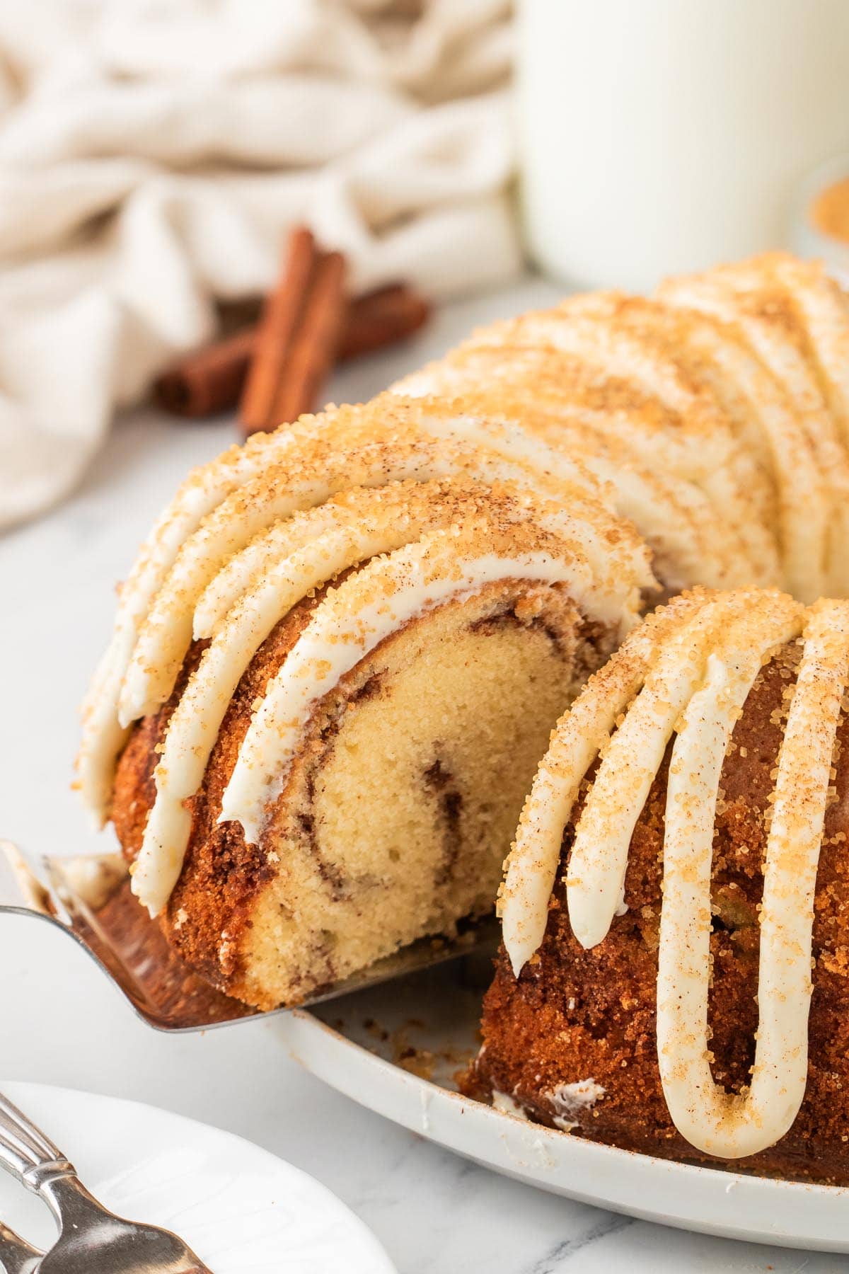 cutting a slice of Snickerdoodle Bundt Cake from a plate. 