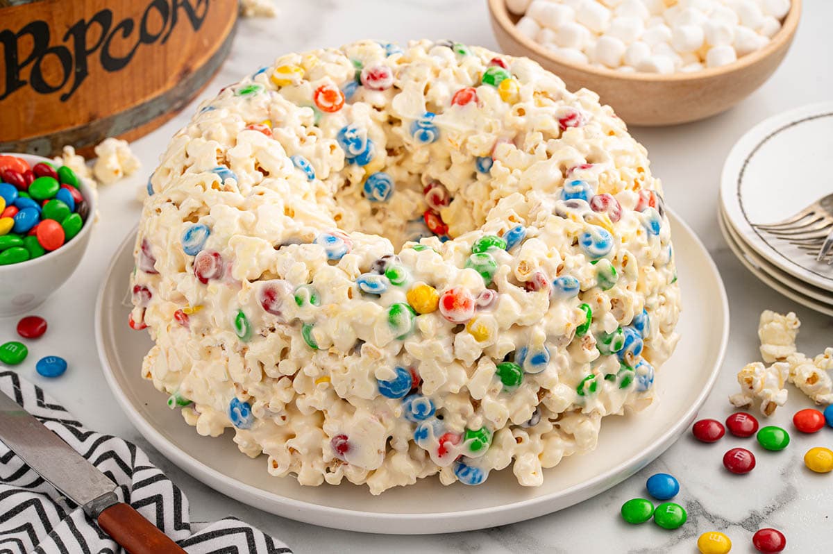 popcorn cake with M&M's and melted marshmallows on a white plate.