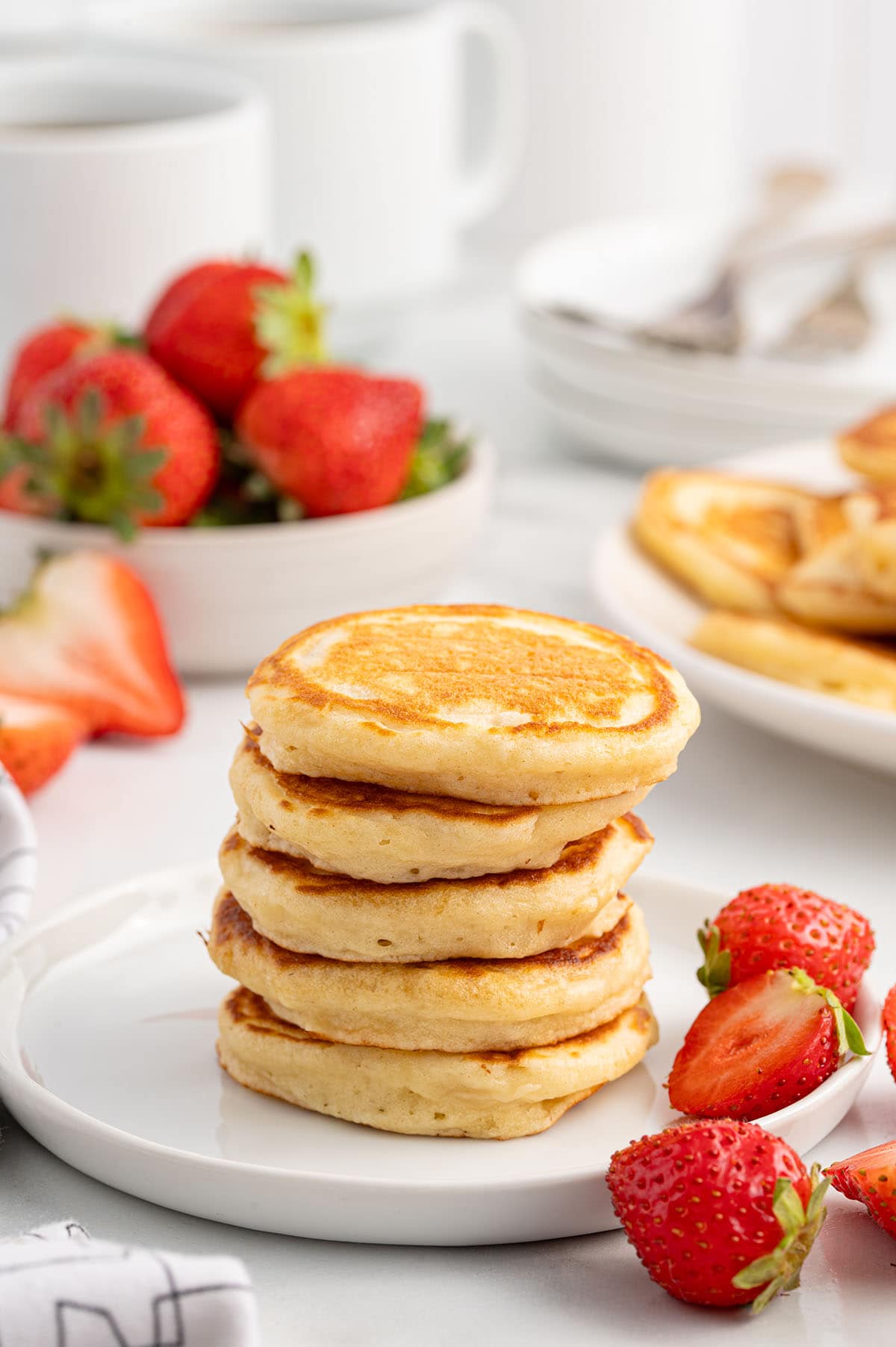 a stack of mini pancakes with strawberries.