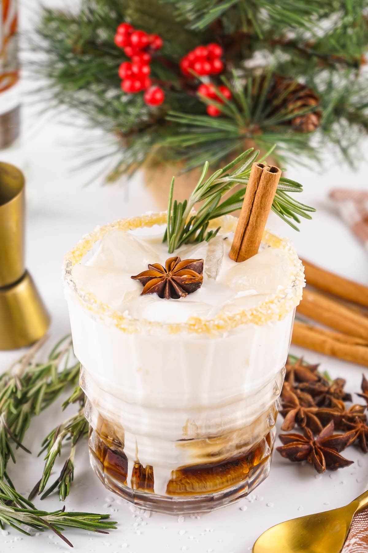 a glass of Salted Caramel White Russian topped with fresh rosemary and a cinnamon stick.