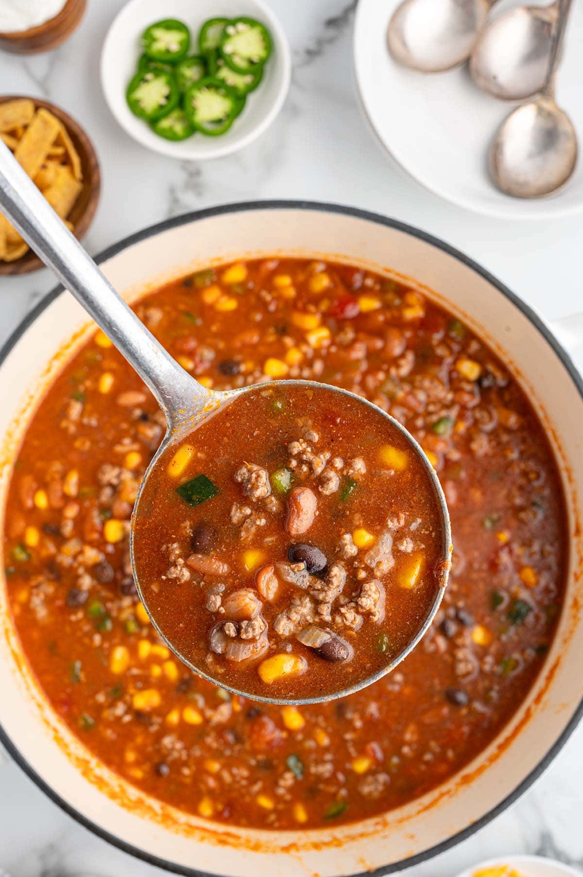 scooping a huge portion of taco soup using a big laddle.