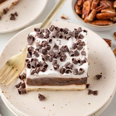 Chocolate delight with chocolate curls on a plate, golden fork, and pecans nearby.