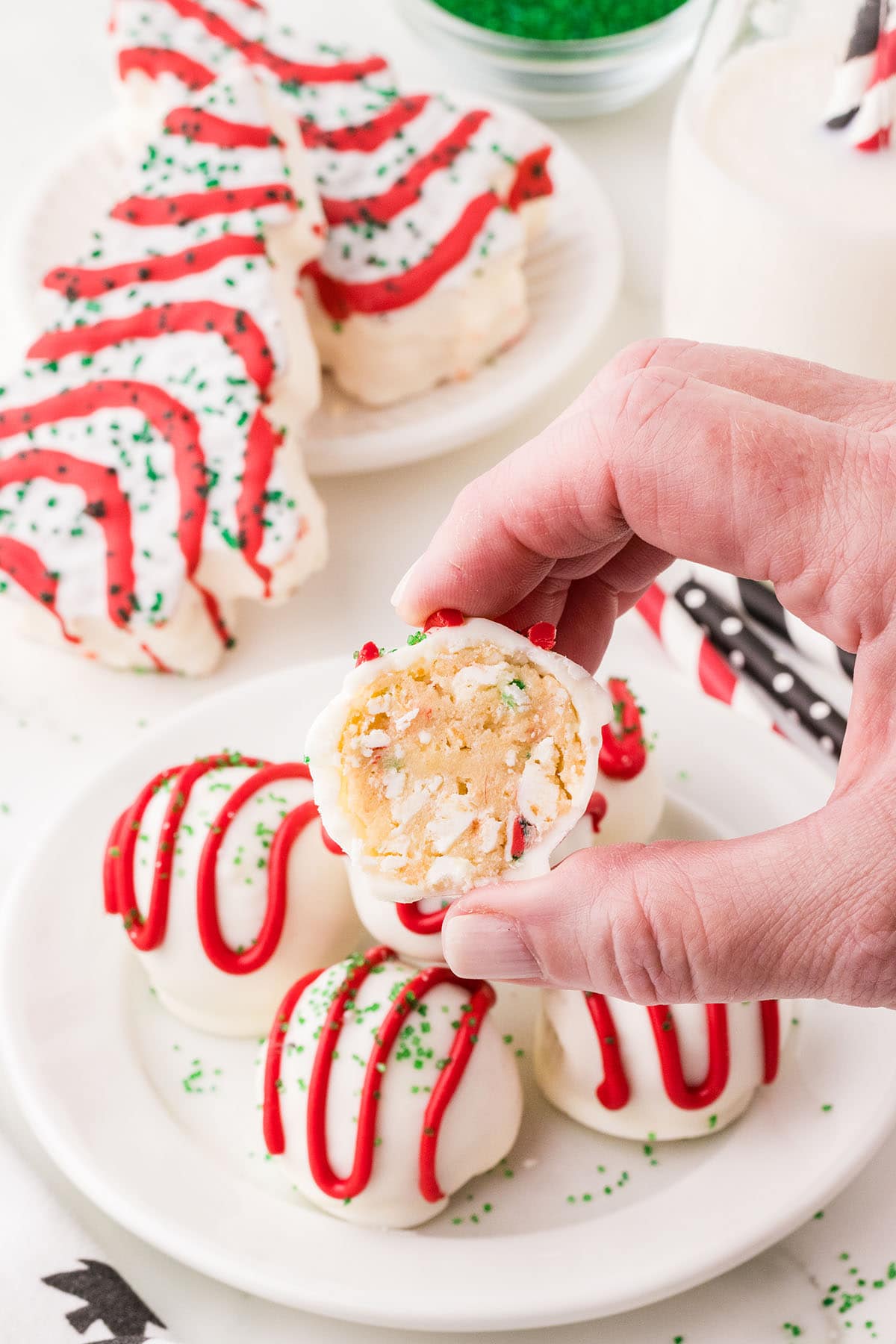 A hand holds little debbie christmas tree cake balls.