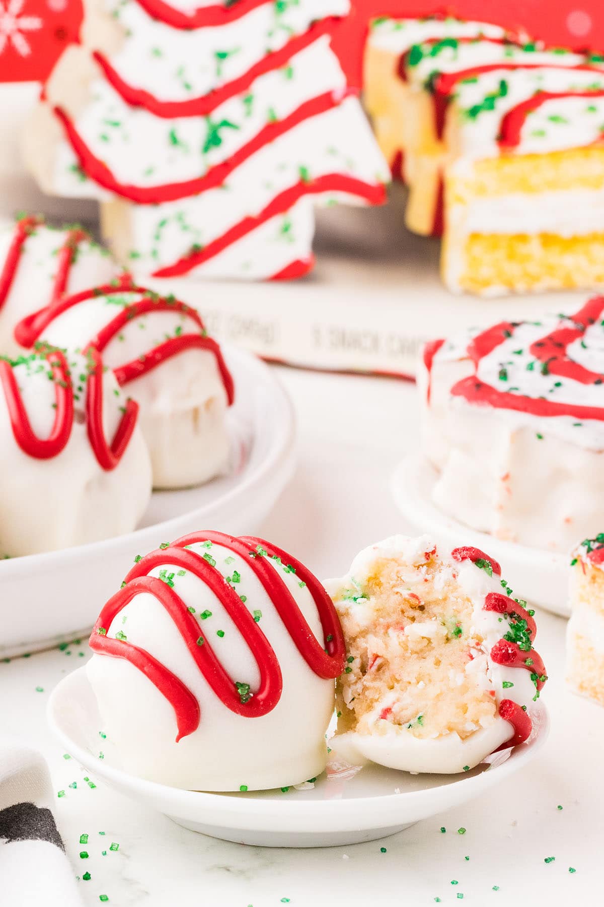 A plate of Little Debbie Christmas Tree Cake Balls, white cake balls topped with festive red and green sprinkles.