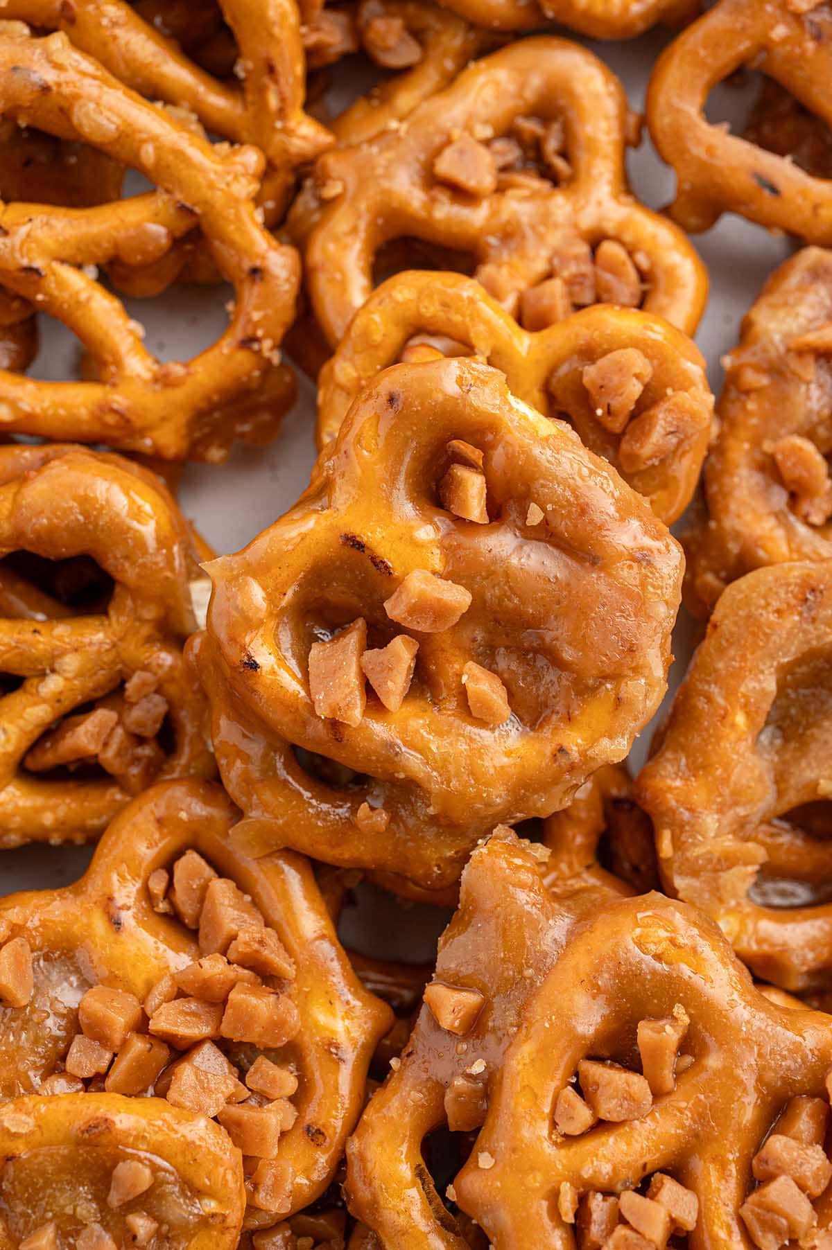 A close-up view of golden butter toffee pretzels topped with crunchy toffee bits.