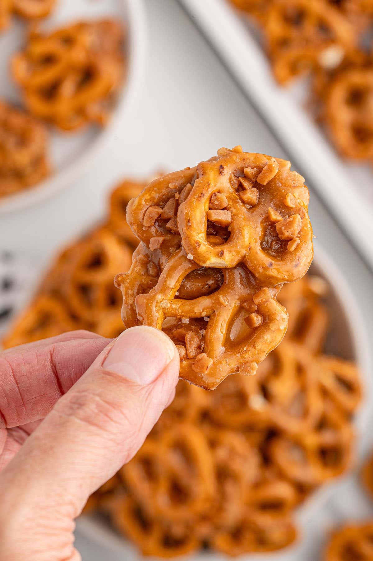 a hand holding a butter toffee pretzel.