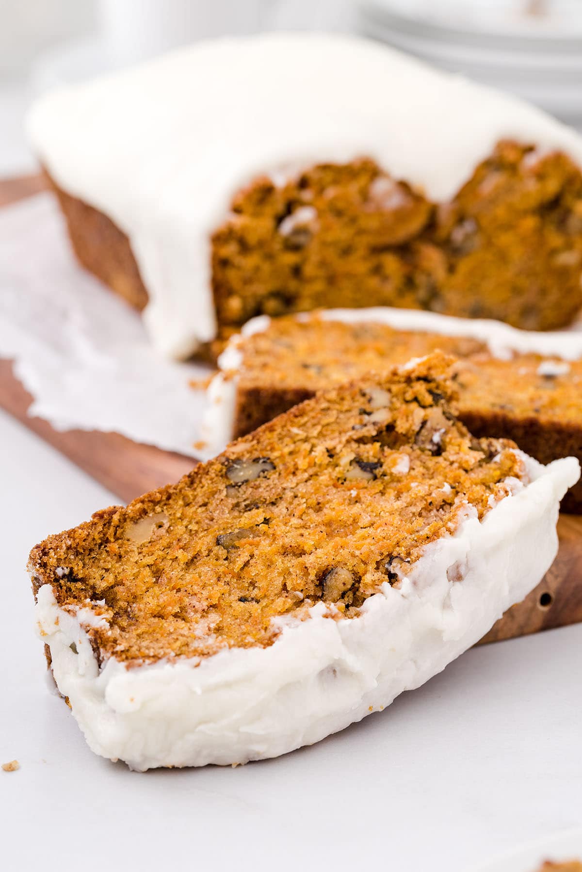 A slice of moist carrot bread covered in a creamy white glaze. 