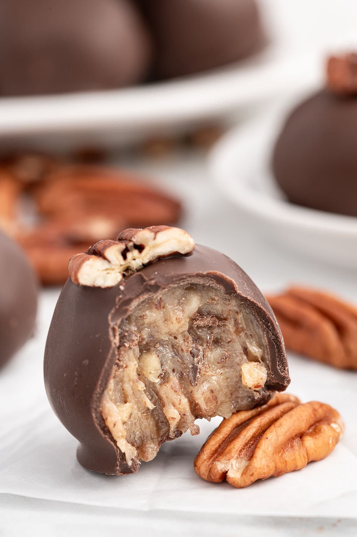 A bitten condensed milk pecan ball coated in chocolate.