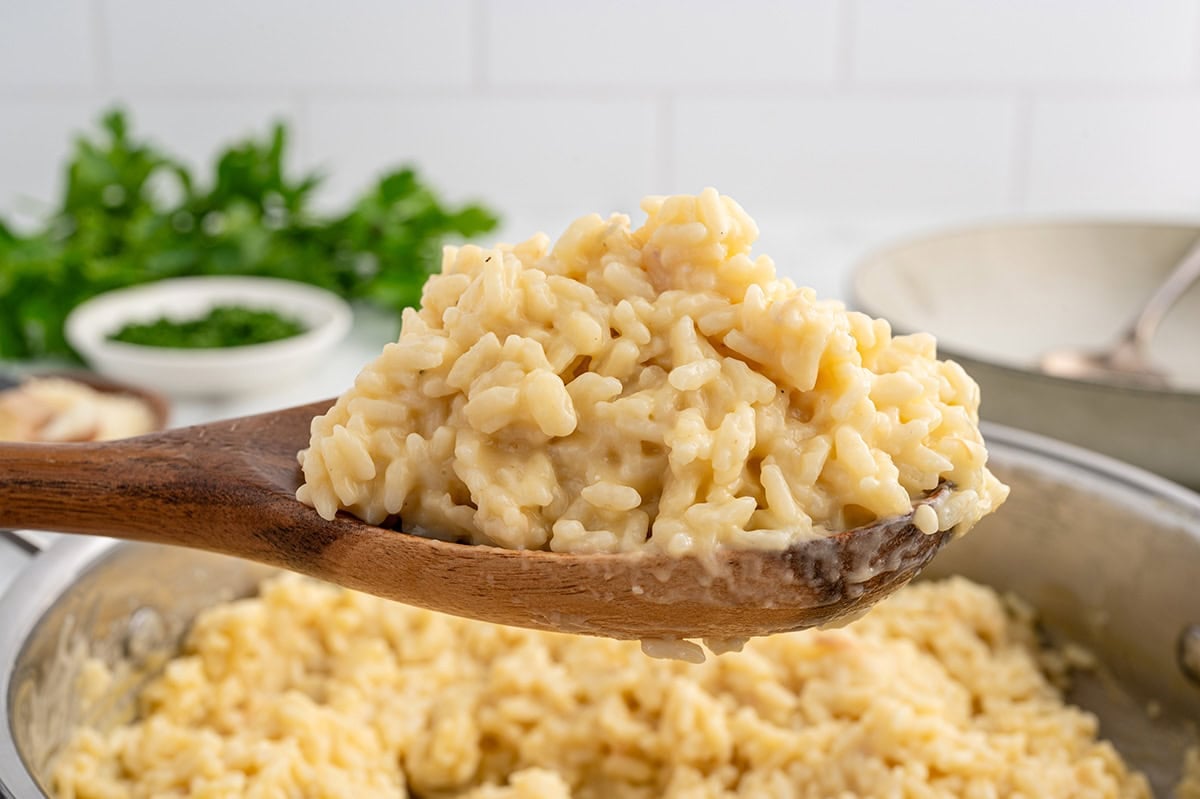 A wooden spoon holding a generous scoop of creamy Souper Rice.