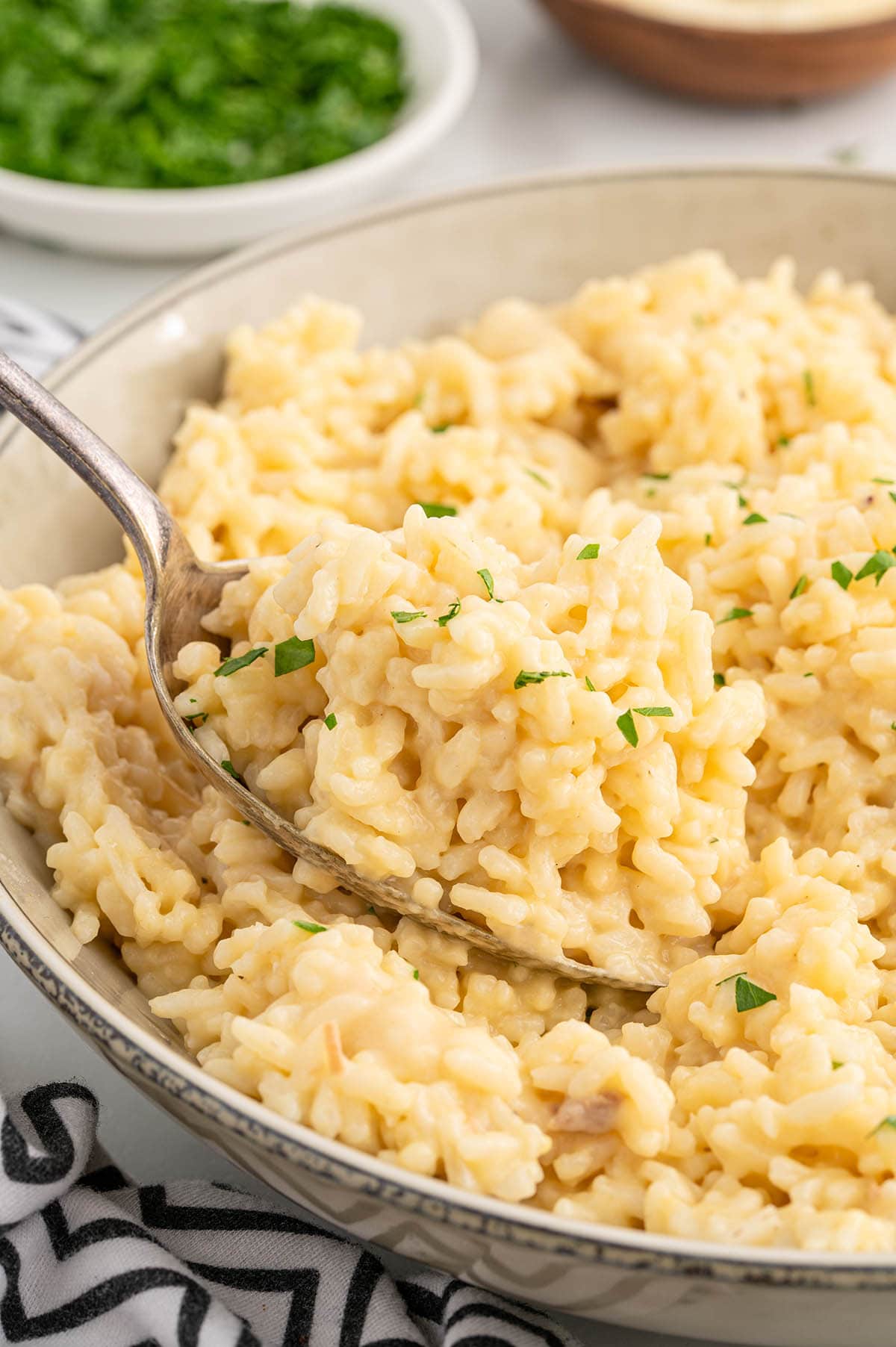 A serving spoon lifting a portion of creamy Souper Rice from a ceramic bowl.