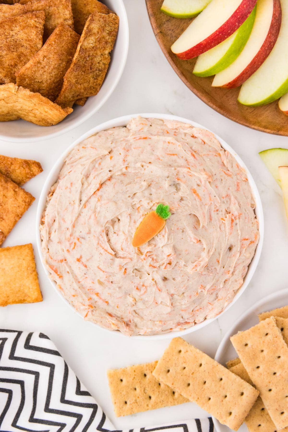 Carrot cake dip served with graham crackers, apple slices, and cinnamon chips.