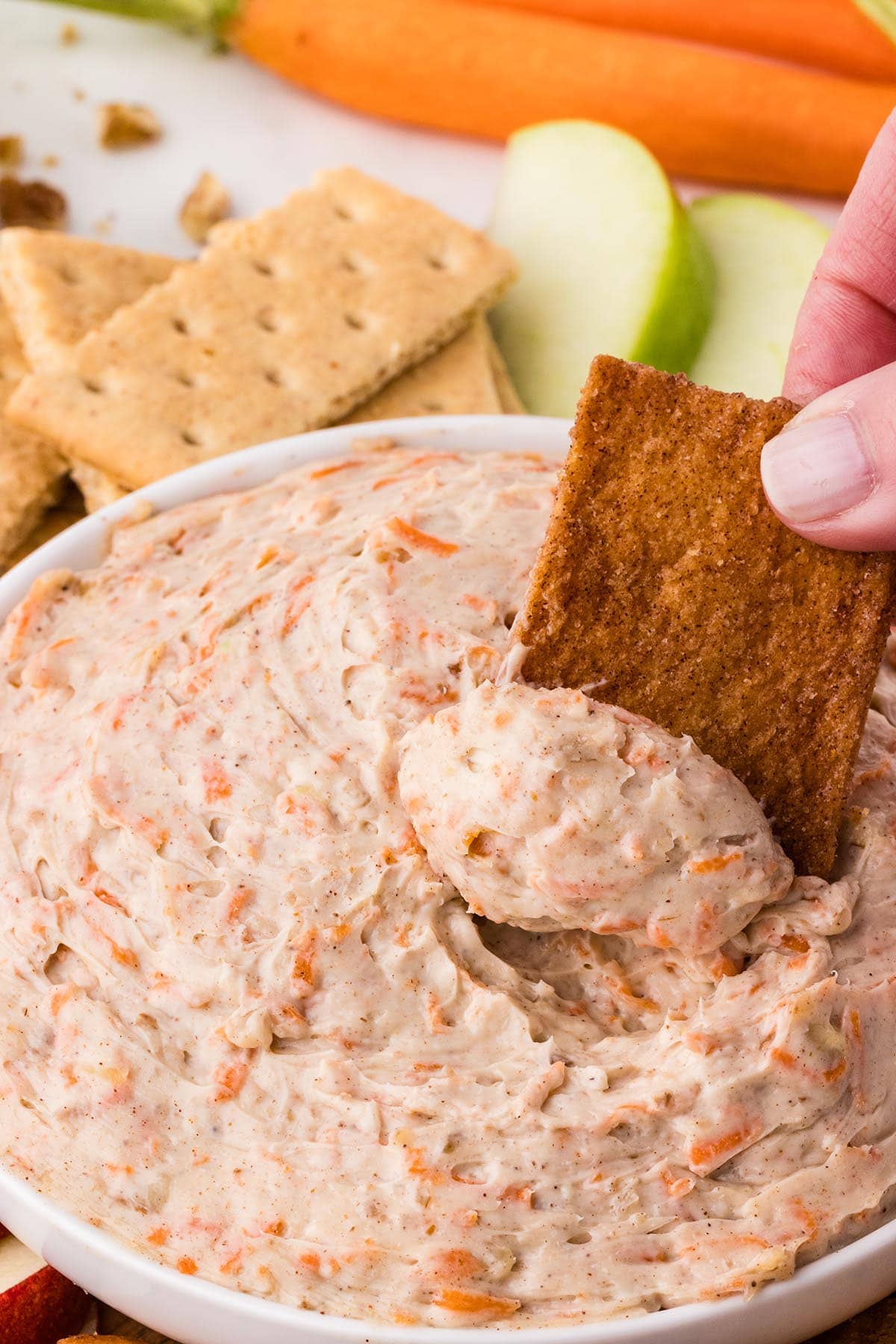 Scooping carrot cake dip with a cinnamon chip.