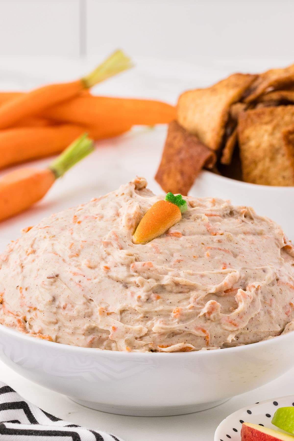 Bowl of carrot cake dip with a decorative carrot on top.