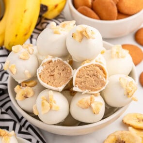 Bowl of Banana Pudding Truffles, with one truffle cut open to show the creamy filling.