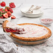 Strawberry Pop Tart Pie with a slice being served, topped with icing and colorful sprinkles.