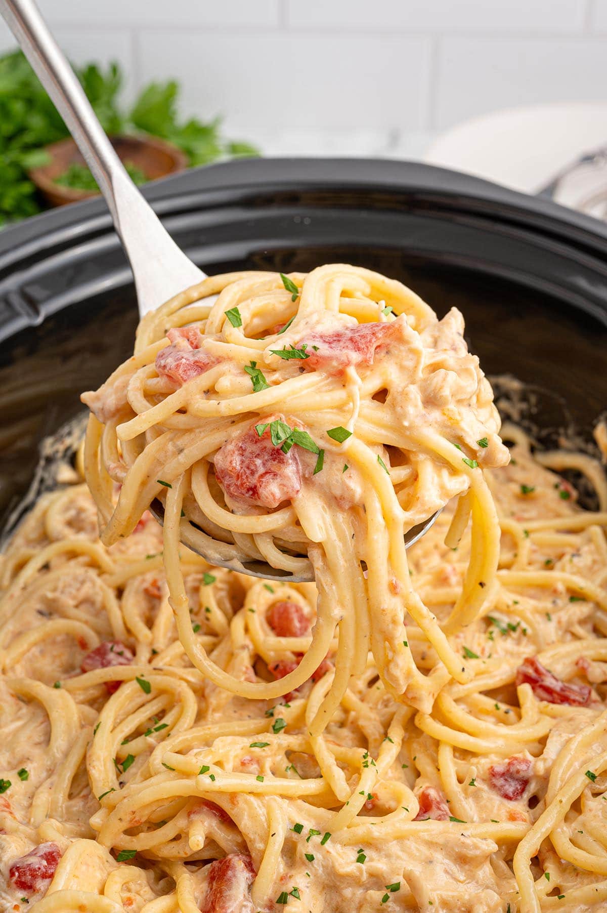 Close-up of chicken spaghetti being served from a slow cooker.