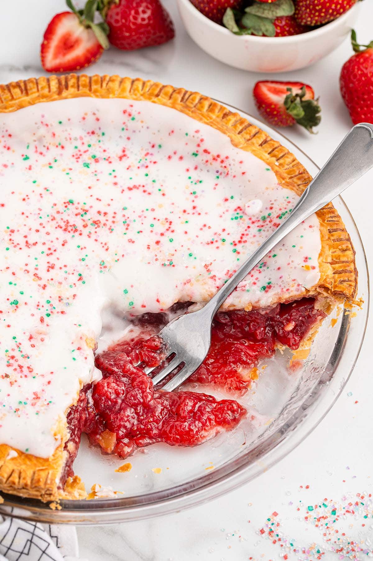 Strawberry Pop Tart Pie with a fork cutting into the filling, surrounded by fresh strawberries.