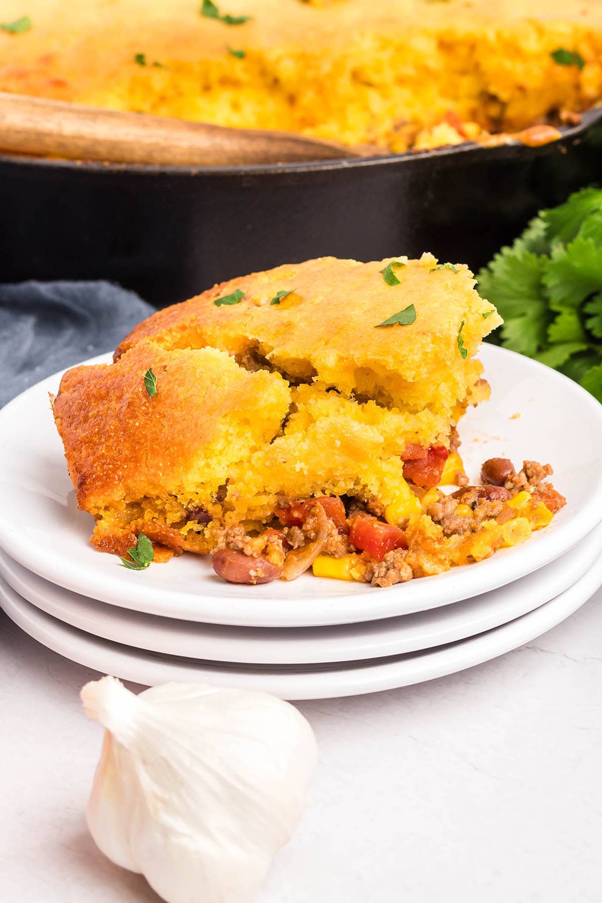 Slice of cornbread cowboy casserole on a white plate with layers of beef, beans, and corn.





