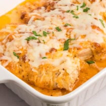 Melt in Your Mouth Chicken in a baking dish, topped with melted cheese and fresh parsley.