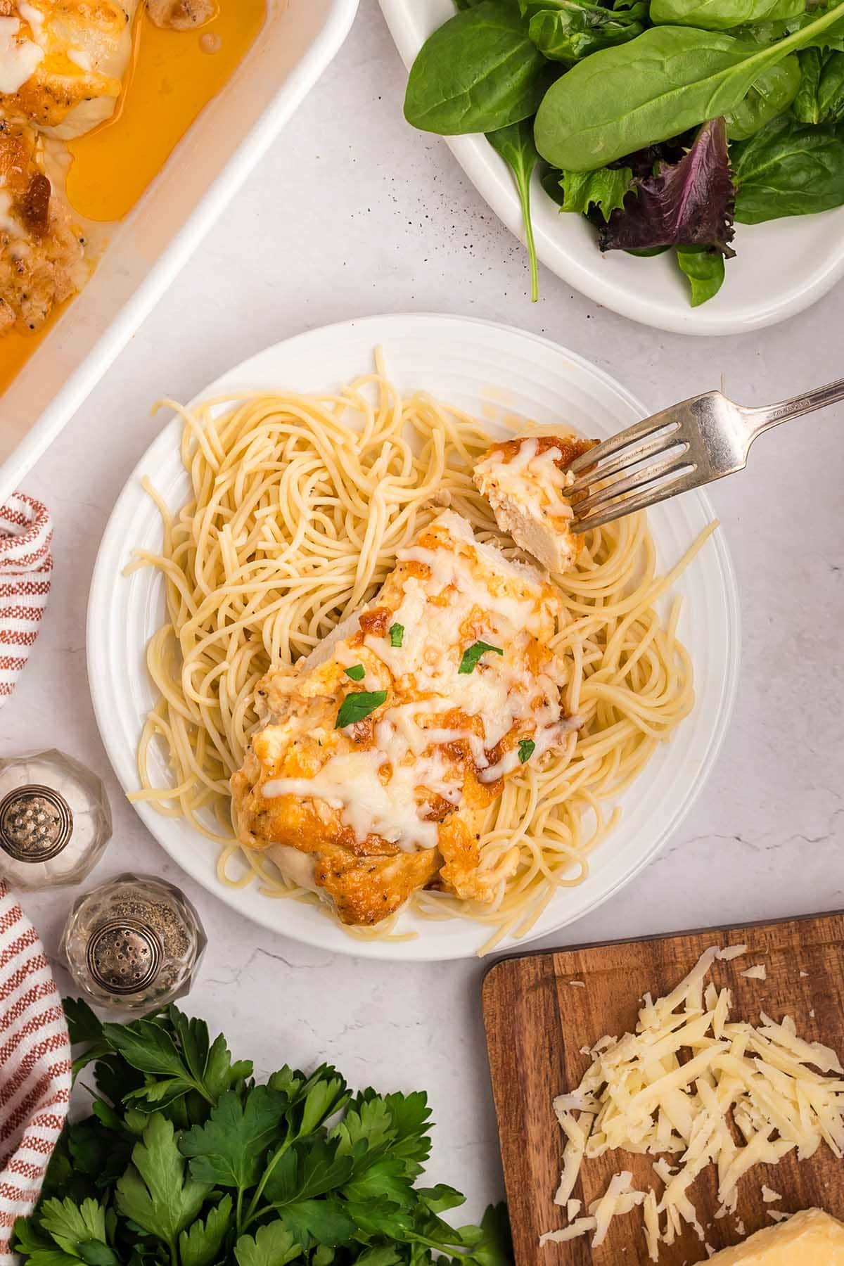 Melt in Your Mouth Chicken served over spaghetti with a fork taking a bite.