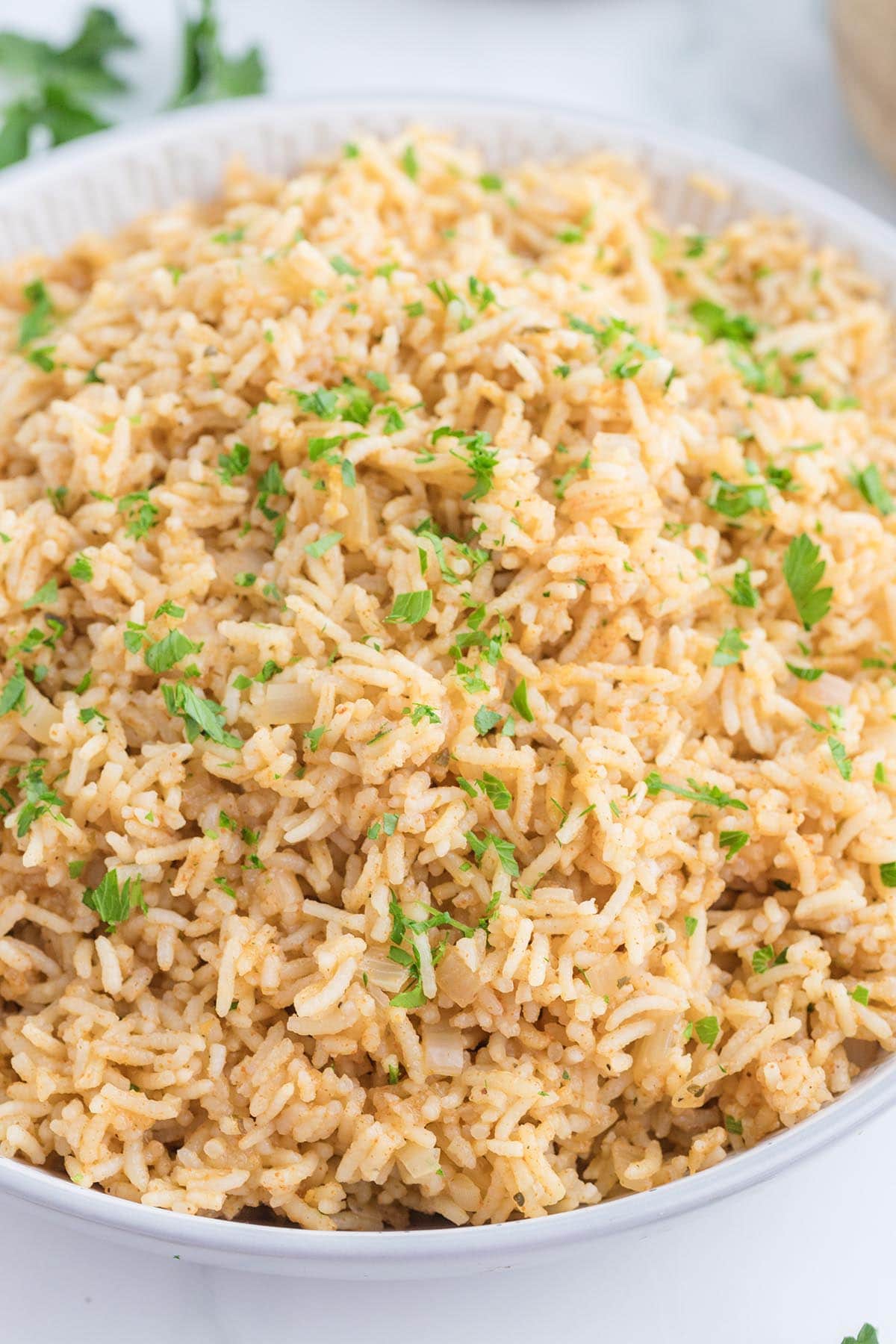 Fluffy seasoned rice garnished with chopped parsley in a white bowl.