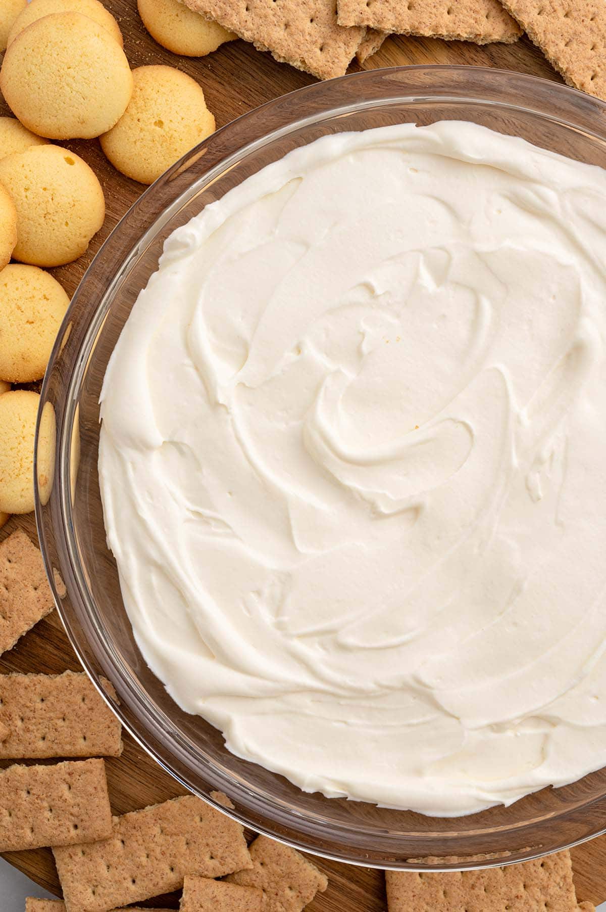 cheesecake dip surrounded with graham crackers on top of wooden serving board. 