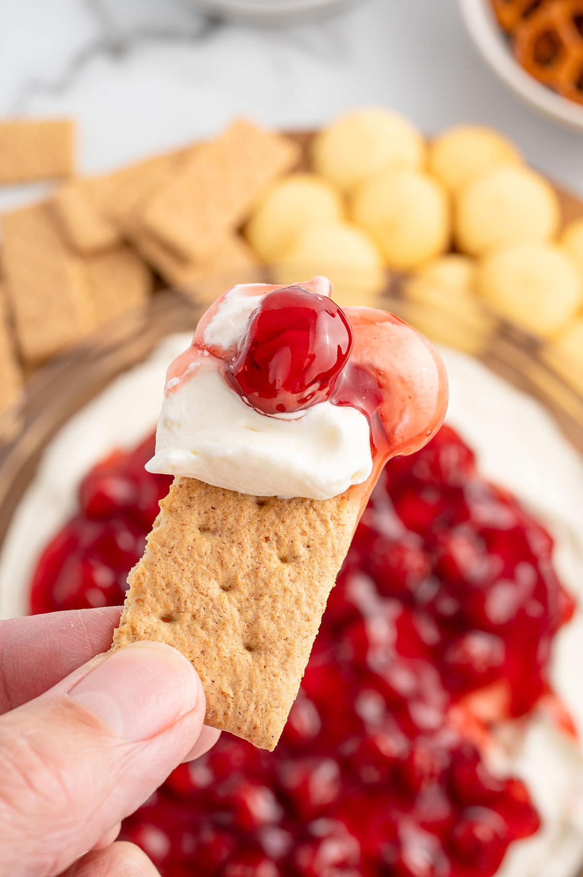 Graham cracker dipped in cherry cheesecake dip.