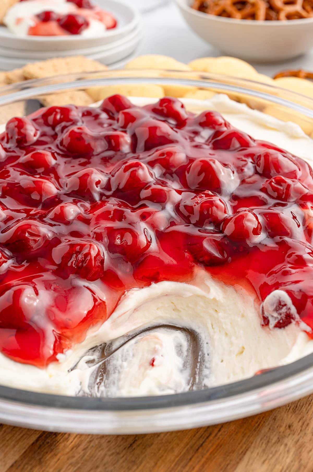 Cherry cheesecake dip in a glass bowl with a scoop taken out.