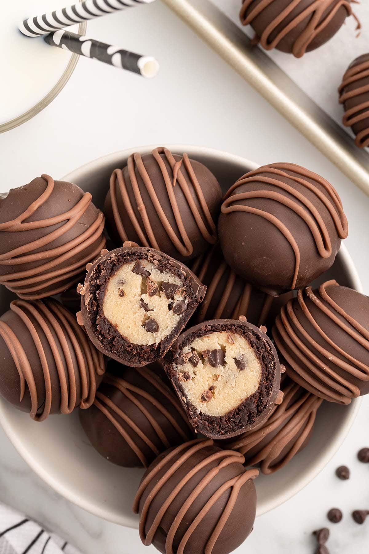 Chocolate chip cookie dough brownie bombs in a bowl, two cut in half to show the filling.