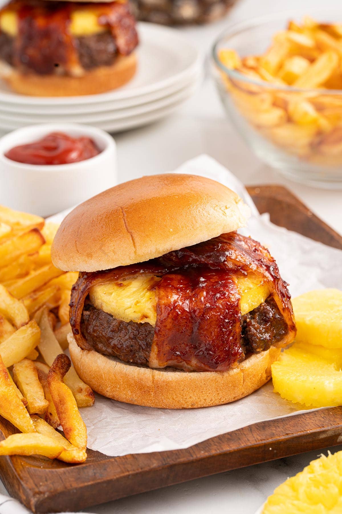 Pineapple bacon burger served with fries and pineapple slices.