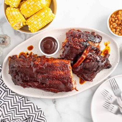 Slow Cooker Baby Back Ribs with barbecue sauce, corn, and baked beans.